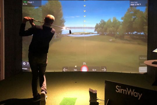 Mies pelaa golfia simulaattorilla